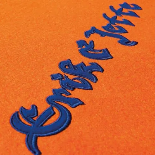 Blauw borduurwerk in reliëf op oranje stof